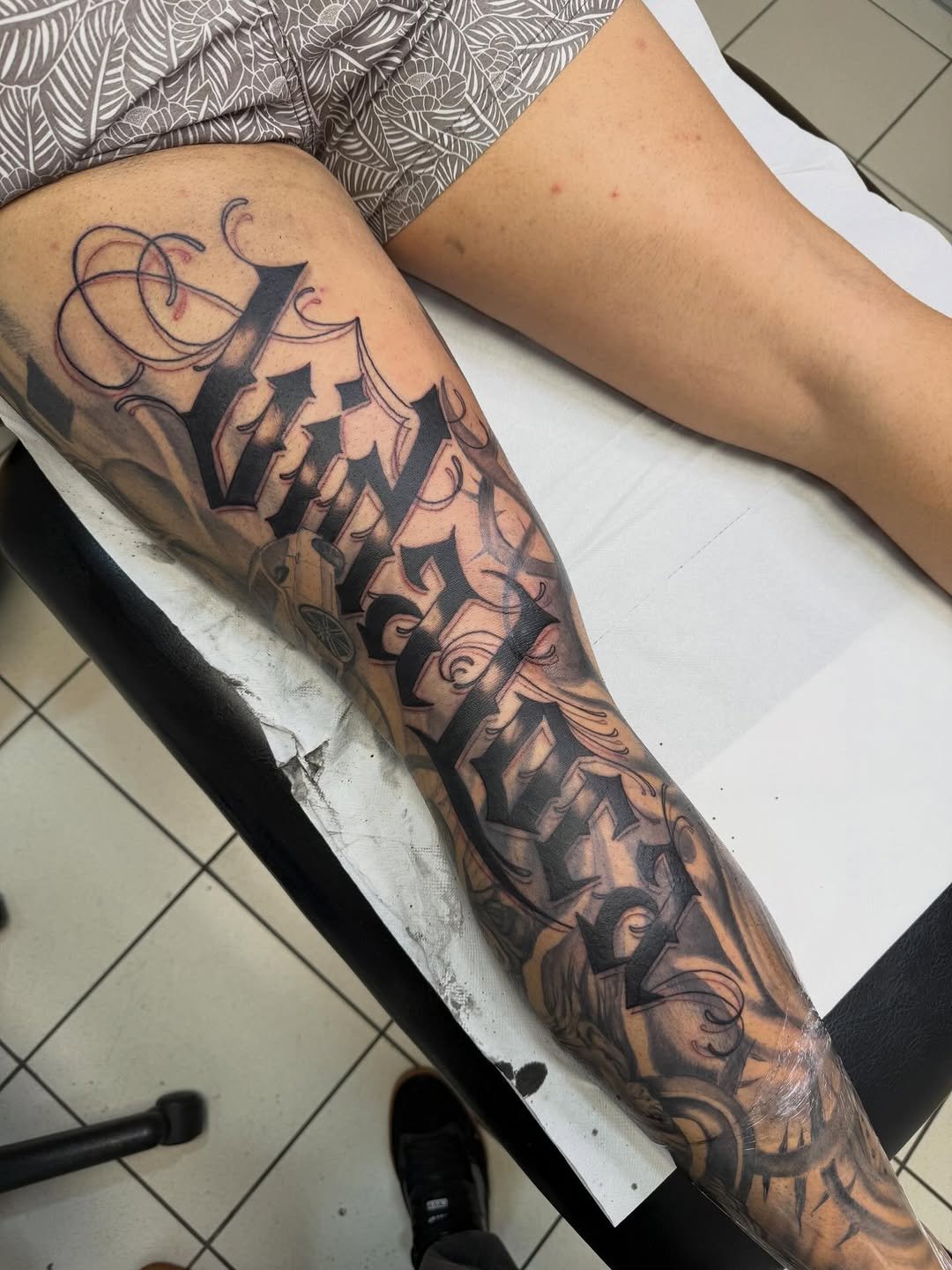 Tatuaje profesional con letras que dicen Vida loca con fondo ornamental en estudio MartinK Tattoo