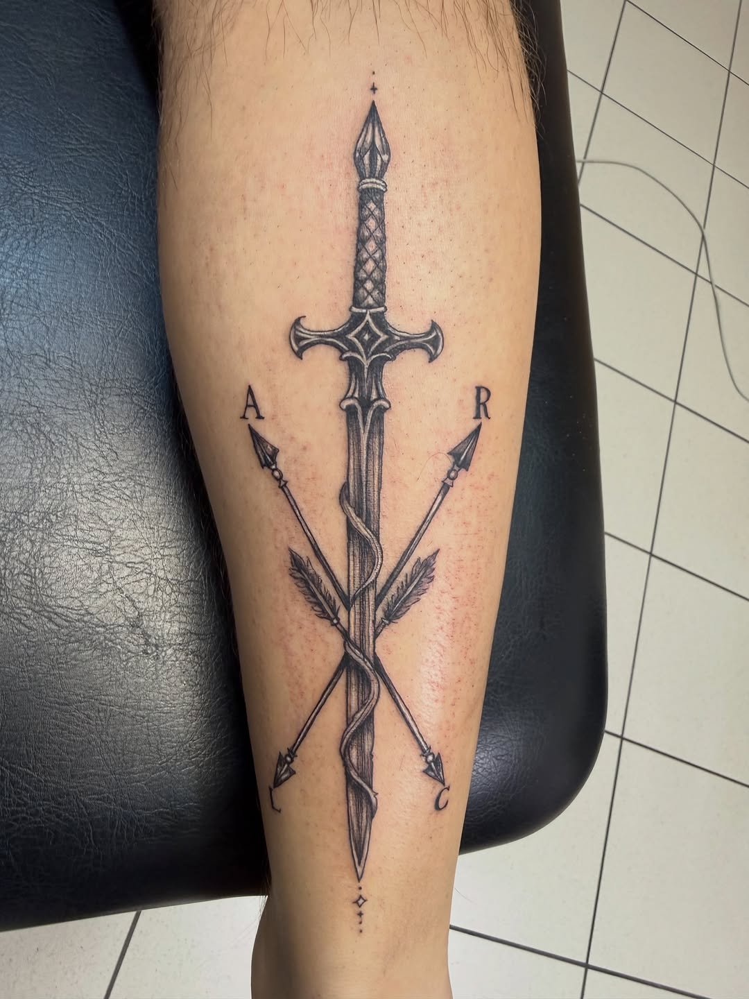 Tatuaje profesional de Espadón con sierpe y flechas cruzadas en estudio MartinK Tattoo