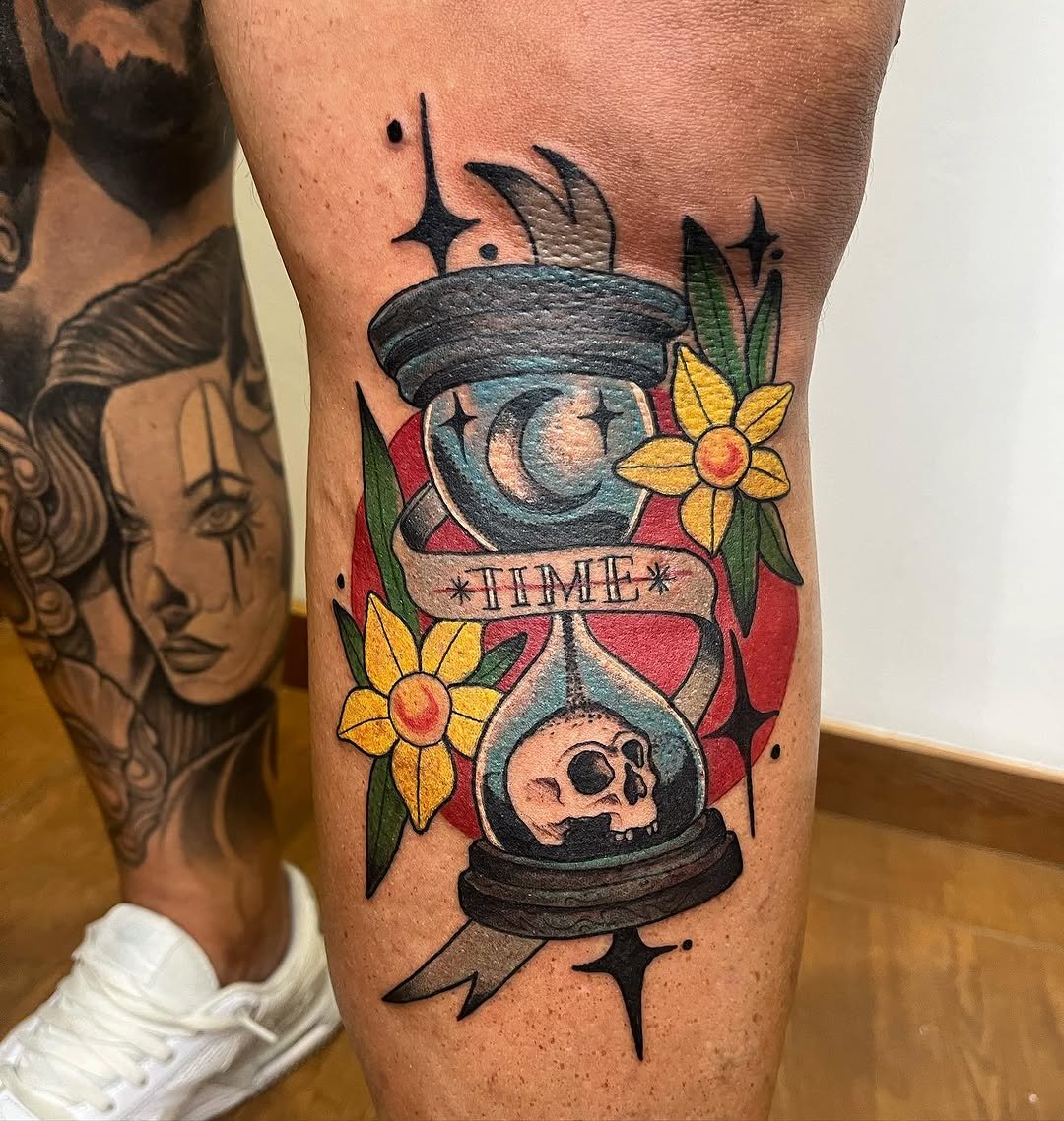 Tatuaje profesional en estudio MartinK Tattoo de un reloj de arena con una calavera, la luna y flores