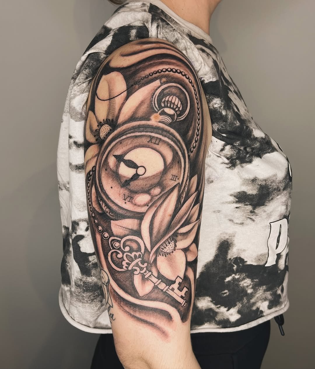 Tatuaje profesional en estudio MartinK Tattoo de un reloj de bolsillo con una llave