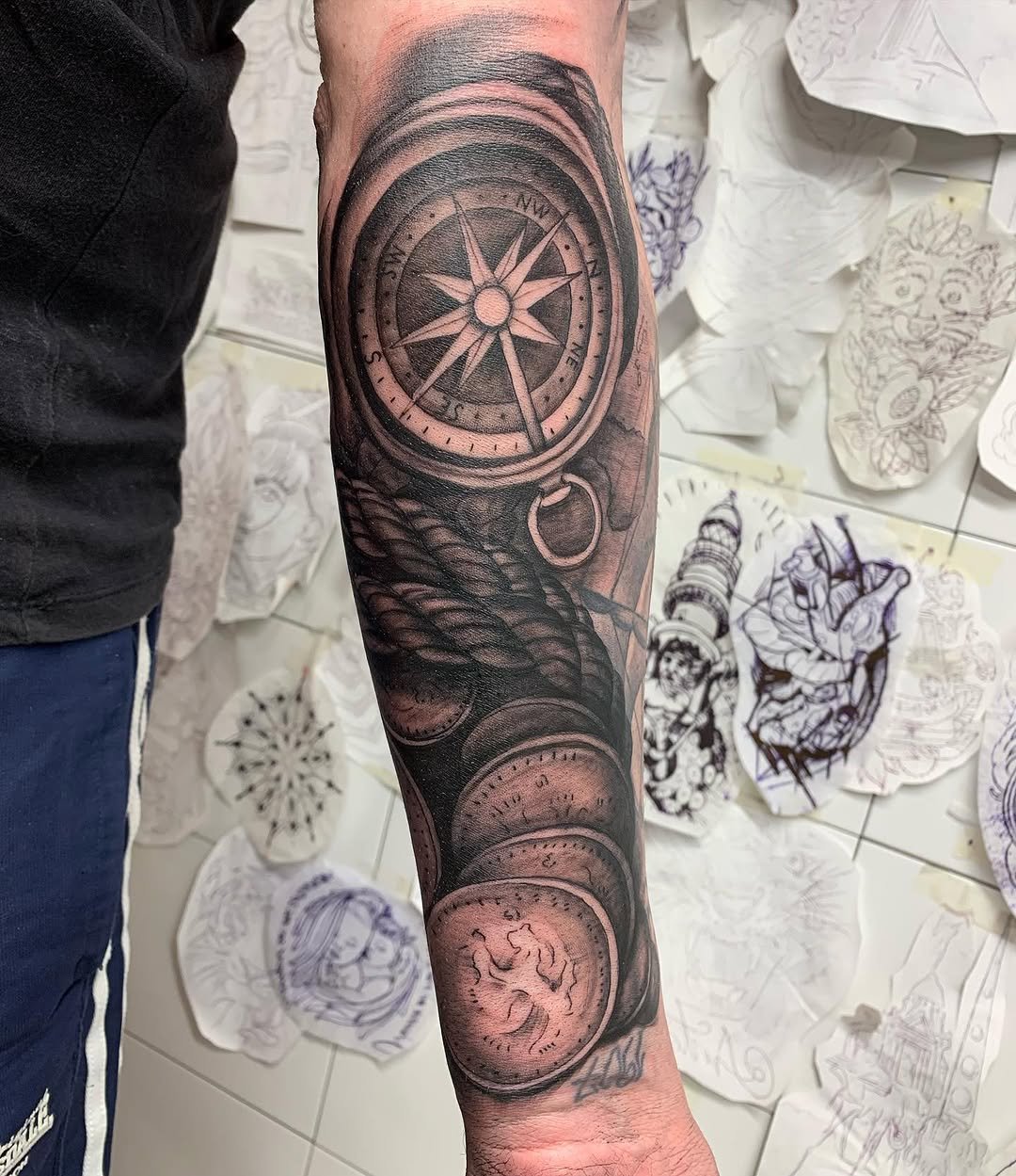 Tatuaje profesional en estudio MartinK Tattoo con una brújula y monedas